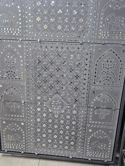 A grey panel featuring intricate Lippan-style mirror work with traditional elephant and floral motifs.