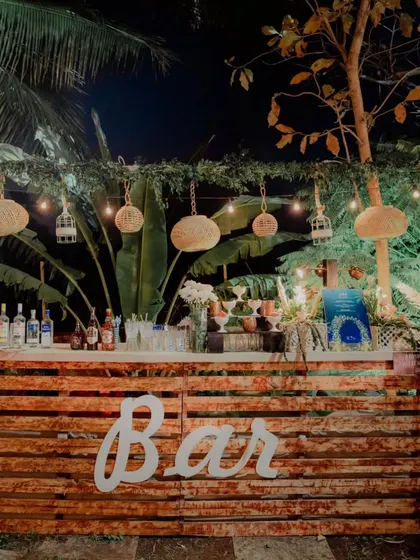A bar that matches the party's vibe. For this rustic-themed engagement, we built a bar from wooden pallets and decorated it with hanging lanterns and birdcages for a charming, relaxed feel.