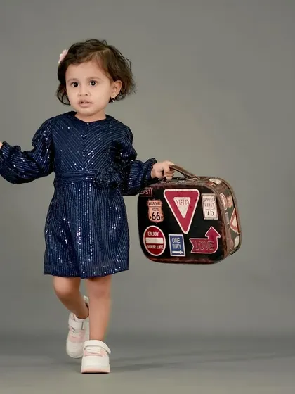 A stylish little girl on the move with her travel-themed suitcase.