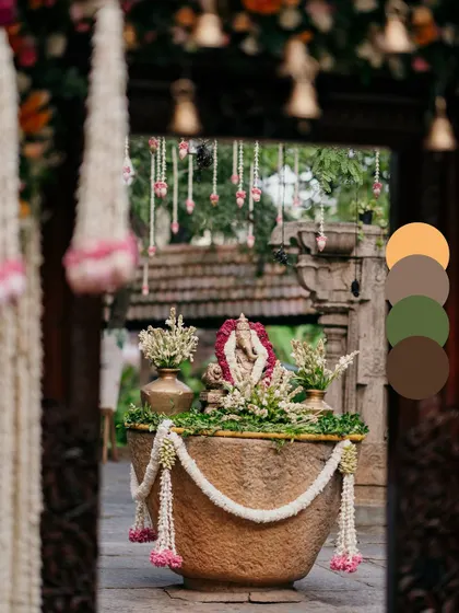 A welcoming entryway featuring a Ganesha idol in a stone urli, adorned with jasmine and lotus garlands. This setup creates a serene and auspicious first impression for guests.