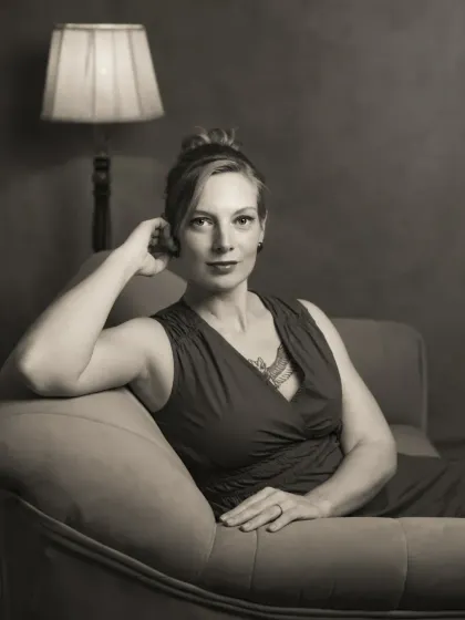 A black and white version of a portrait of Sonia on a chaise lounge. The monochrome treatment enhances the classic, cinematic feel of the image, focusing on her expression and the elegant lines of the pose.