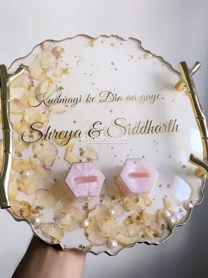 A close-up of the engagement ring platter, showing the preserved flowers, pearls, and custom song lyrics. Every detail is designed to tell the couple's unique story.