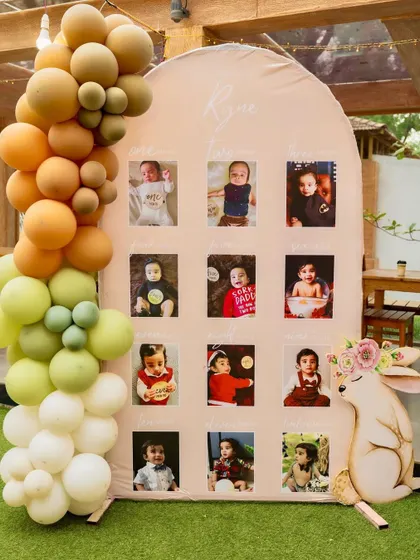 A milestone photo board for Ryne's first birthday, decorated with a balloon garland and a cute rabbit cutout.