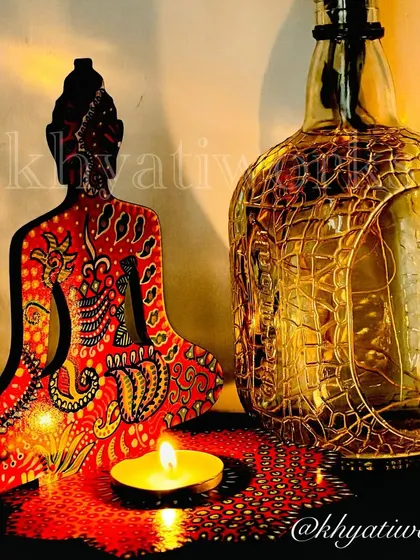 A close-up of the red Buddha candle holder. The detailed dot work and patterns are all painted by hand, making each piece a unique work of art.