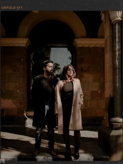 A moody, cinematic shot of the couple against old architecture, using shadows and light to create drama.