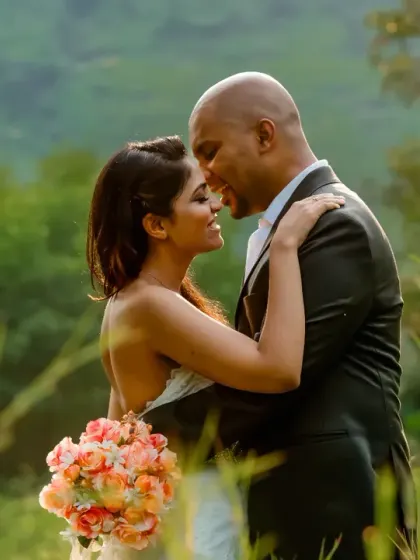 An intimate embrace surrounded by the soft, green hues of nature. The warm sunlight filters through the grass, creating a dreamy and romantic atmosphere for this close-up portrait.