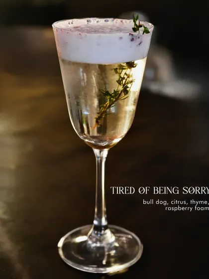 'Tired of Being Sorry', a gin-based cocktail with citrus, thyme, and a raspberry foam.