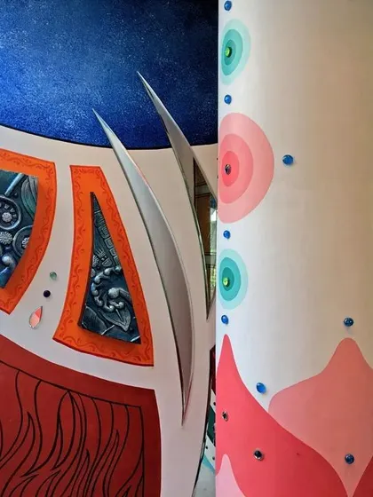 This view shows how the abstract design flows from the wall onto the pillar, creating a continuous piece of art that envelops the space. The use of bright, contrasting colors makes the entrance feel dynamic.