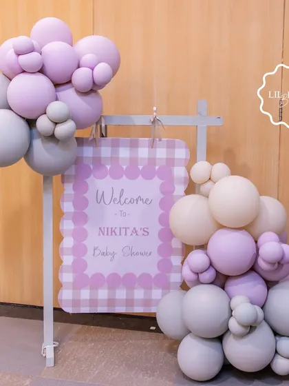 A charming welcome sign for Nikita's baby shower, featuring a gingham print and soft pastel balloon clusters to greet guests with style.