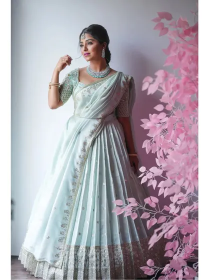 A beautiful shot of the mint green half-saree, with a pink tree prop adding a touch of modern artistry.