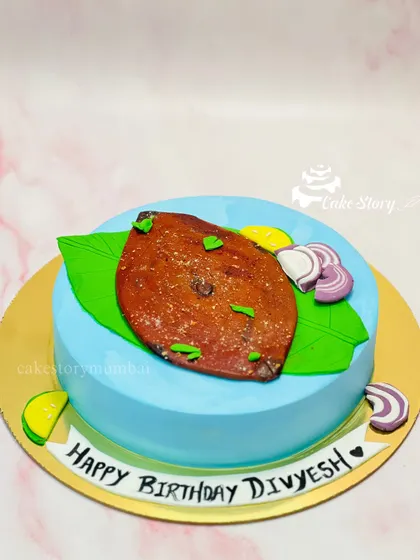 The final Surmai Fry cake, served on an edible banana leaf with slices of onion and lemon. It’s a perfect example of a truly personalized and hatke cake.