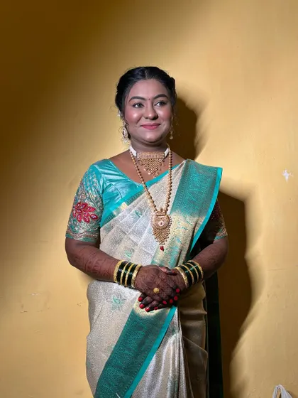 A full portrait of the bride, looking elegant and radiant in her off-white and teal saree.