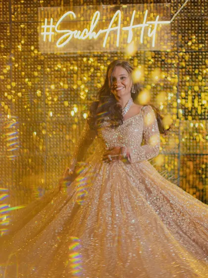 The bride twirls in her shimmering gown in front of a custom neon sign and a glittering gold backdrop. A perfect shot for a glamorous cocktail night.