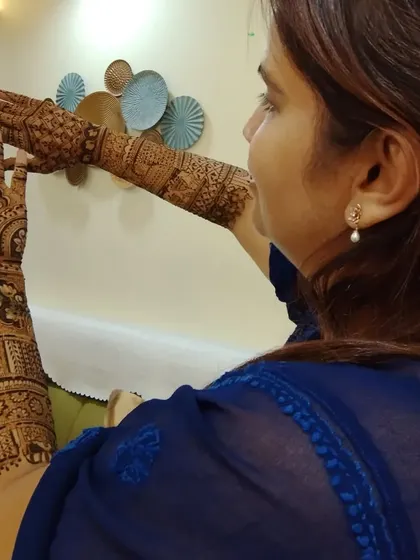 A bride showing off her full arm mehandi. The design includes both floral and traditional motifs.