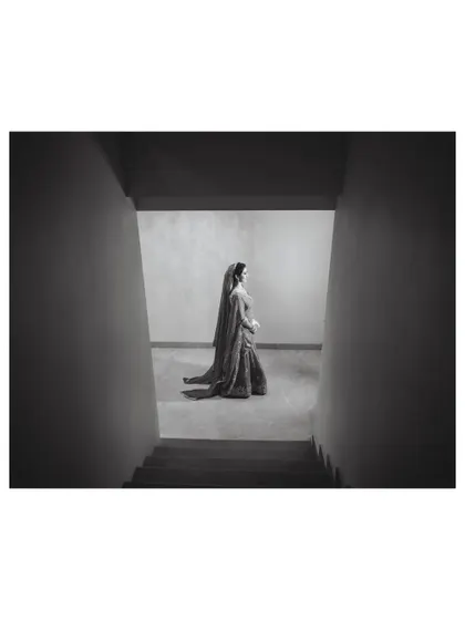 A minimalist and powerful black and white composition, using the stark architecture to frame the bride and create a sense of solitude and elegance.