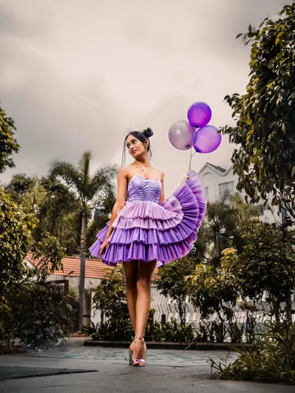 A full shot showing the beautiful tiered purple dress in a garden setting.