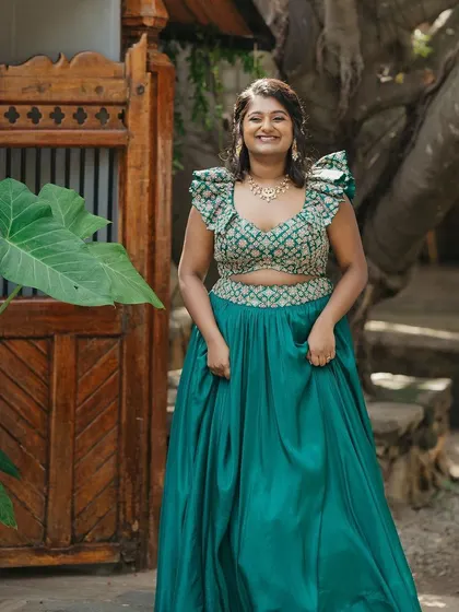 The bride looks stunning in her emerald green lehenga, posing for a photo before her Mehendi ceremony.