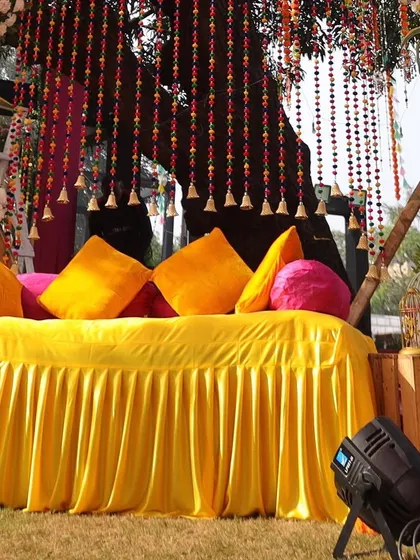 The main seating for the Haldi ceremony. A comfortable yellow-draped sofa is decorated with bright cushions and beautiful beaded hangings, creating the perfect spot for the bride and groom.