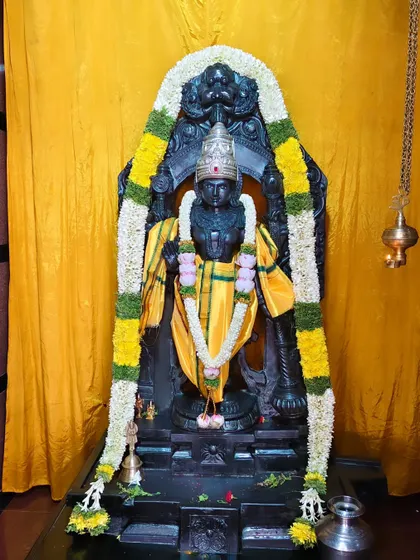 The idol of Satyanarayana Swamy dressed in yellow silk and adorned with a simple, elegant flower garland.
