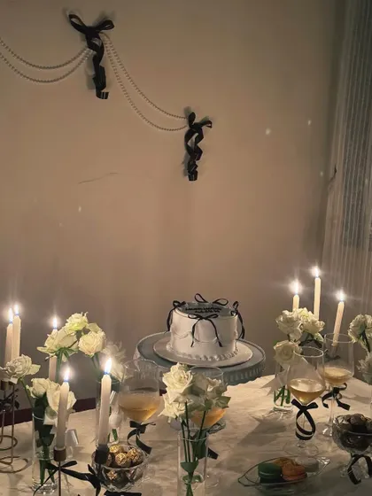A closer look at our black and white themed table. This aesthetic is achieved with white roses, black ribbon details on the cake and glassware, and the soft, romantic light of tapered candles.