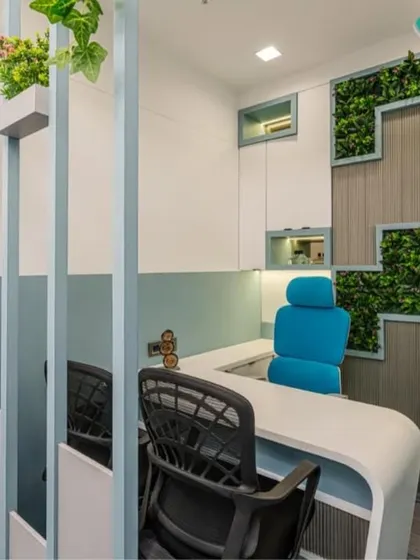 This private cabin combines functionality with biophilic design. A vertical garden is integrated into the storage unit, bringing nature indoors. The clean lines of the white desk and the pops of color from the chair create a fresh, modern, and productive workspace.