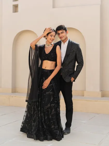 A classic black-on-black look for a cocktail event. Her sequin lehenga and his patterned tuxedo create a sophisticated and glamorous vibe.