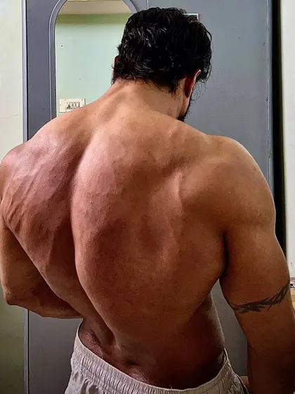 A classic back lat spread pose, emphasizing the V-taper and overall back development.
