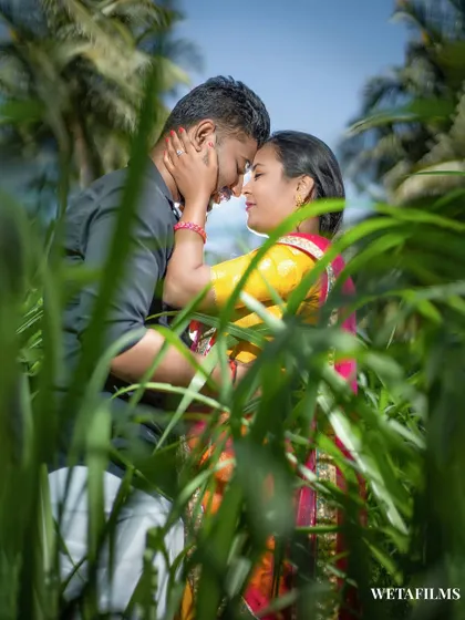 An intimate pre-wedding moment captured through tall green grass. This framing creates a private, secret-garden feel for this countryside couple shoot.