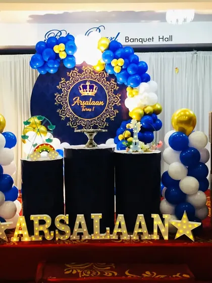 A royal blue and gold theme for Arsalaan's first birthday. The elegant backdrop and balloon pillars create a regal and celebratory setting for the little prince.