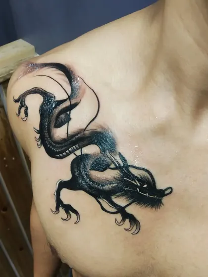 Another angle of the dragon tattoo, showing the flow and shading. This style uses negative space and smoky effects to create depth and a mystical feel.