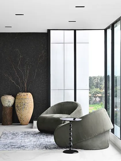 This corner lounge area in a high-end office suite is all about the view. Full-height windows flood the space with light, while the minimalist furniture and textured black wall create a dramatic contrast.