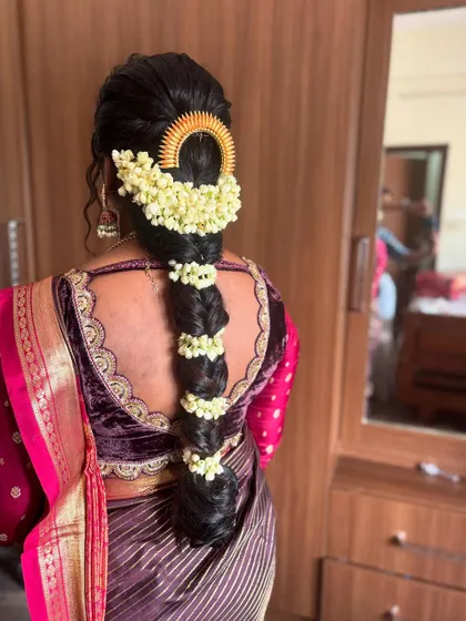 A traditional braid decorated with fresh jasmine flowers and a golden hairpiece. This style is perfect for a wedding or any festive occasion.