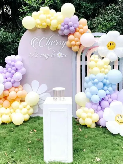 A cheerful and modern 'Half way to one' setup with daisy-themed balloon art and a pastel color palette.