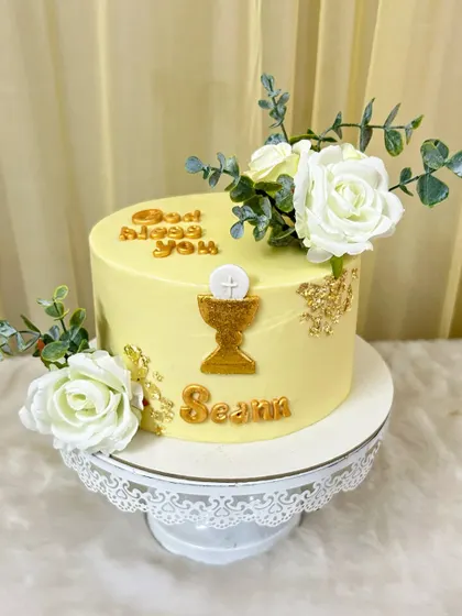 A beautiful cake for a First Holy Communion. The design features a golden chalice, the message "God Bless You," and elegant white roses.