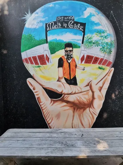Our signature art piece at Melt in Cafe, featuring a self-portrait of one of our artists within a reflective sphere held by a hand.