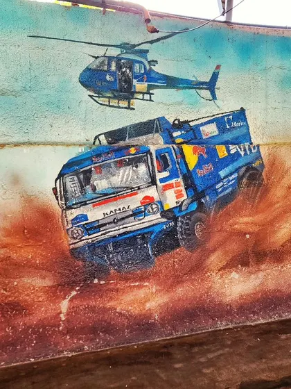 A detailed shot of the rally truck and helicopter from the Burnout Café mural, showcasing the dynamic action and realism in the painting.