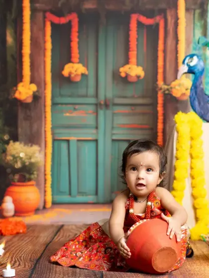 A playful moment as our little Gopi explores the set, holding a small clay pot. Candid shots like this are a wonderful part of every child's photoshoot.