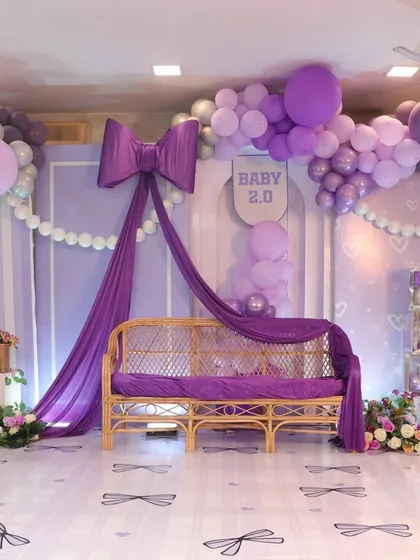 For this baby shower, we went with a trendy and elegant purple bow theme. The large fabric bow and draping created a stunning focal point.