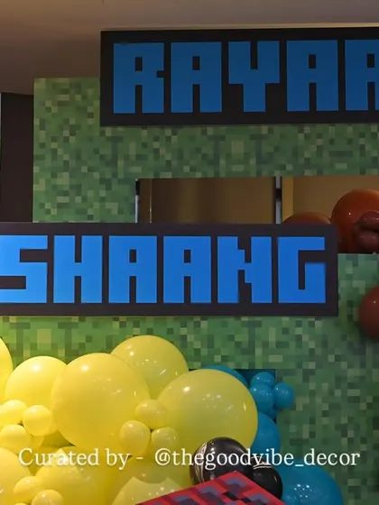 Custom name signs in the classic Minecraft font, placed against a pixelated green backdrop to personalize the gaming-themed birthday party.