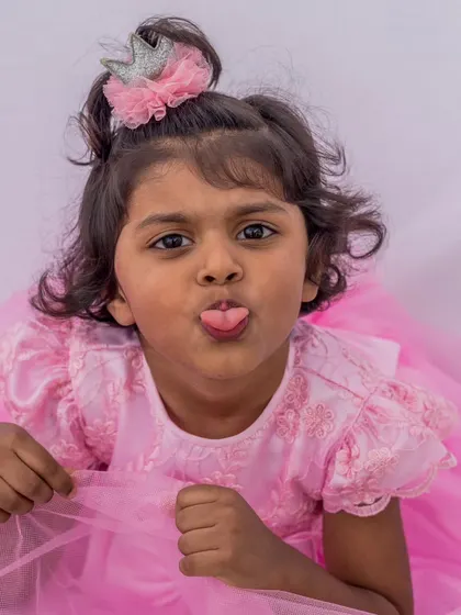 A close-up portrait of a little princess in her pink party dress. The soft color and delicate embroidery on the sleeves are perfect for capturing her sweet and playful nature.