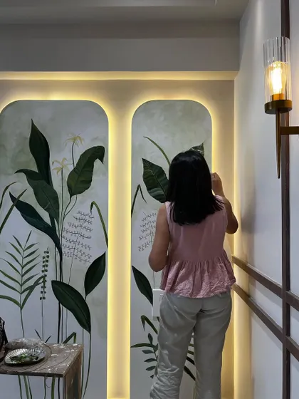 A final look at a botanical mural painted on two arched panels in a residential hallway. The backlighting enhances the artwork, making the lush green leaves and delicate flowers glow.