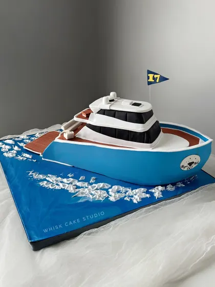 A 5 kg yacht cake for a nautical-themed celebration. This sculpted cake is a detailed replica of a luxury yacht, complete with waves made of white chocolate.