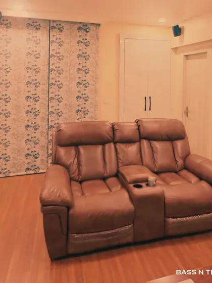 A cozy living room transformed into a home theatre with a Sonos wireless surround sound system. The compact satellite speakers and recliner create a perfect spot for Netflix nights.