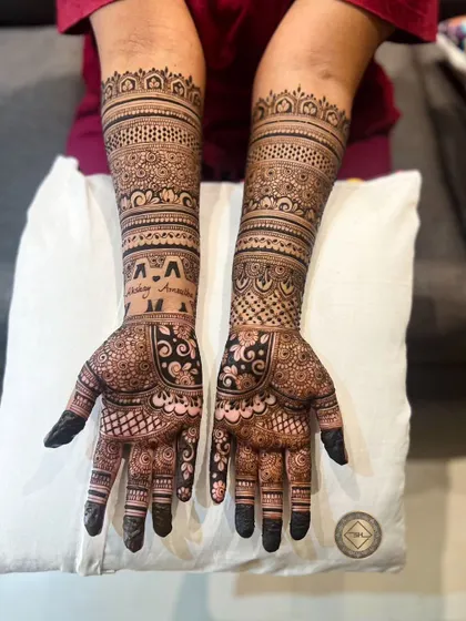 This intricate henna design extends up the forearms with multiple bands of detailed patterns. We also included the couple's initials, 'Akshay' and 'Amrutha', for a personal touch.