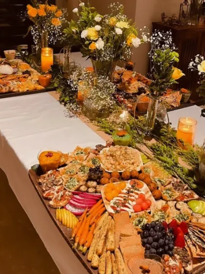 Flowers and candles sit between our grazing boards in this evening spread, with crackers, dips and little bites along the table.