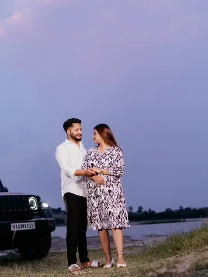 A modern maternity portrait of a couple standing by their car against a dusky sky. This shot has a casual, adventurous feel, perfect for couples who want something different.