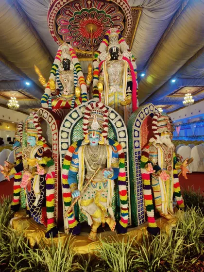 An elaborate setup of deity statues, intricately decorated with colorful flowers and fabrics. This is a beautiful way to create a divine ambiance for a wedding or major pooja ceremony.