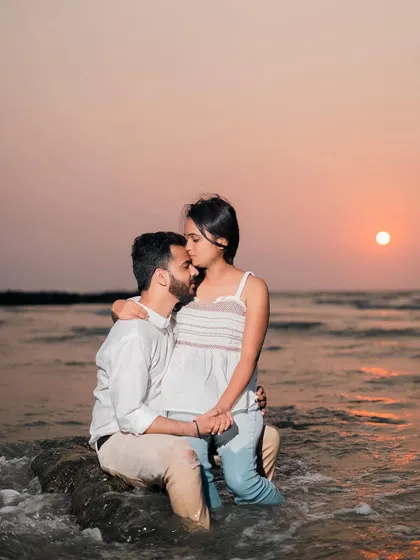 Another angle of the romantic sunset kiss. This close-up focuses on the intimacy of the moment, with the beautiful orange sky in the background.