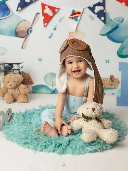 This little aviator is flying high into his second year. The complete setup with a vintage plane backdrop and 'ONE' sign made for an adventurous first birthday portrait.