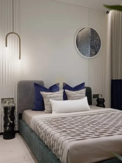 A close-up of the bed styling, where we incorporated the EON Group's signature blue through velvet pillows. This is paired with a textured bedspread and a sleek, arched pendant light for a modern and cohesive look.